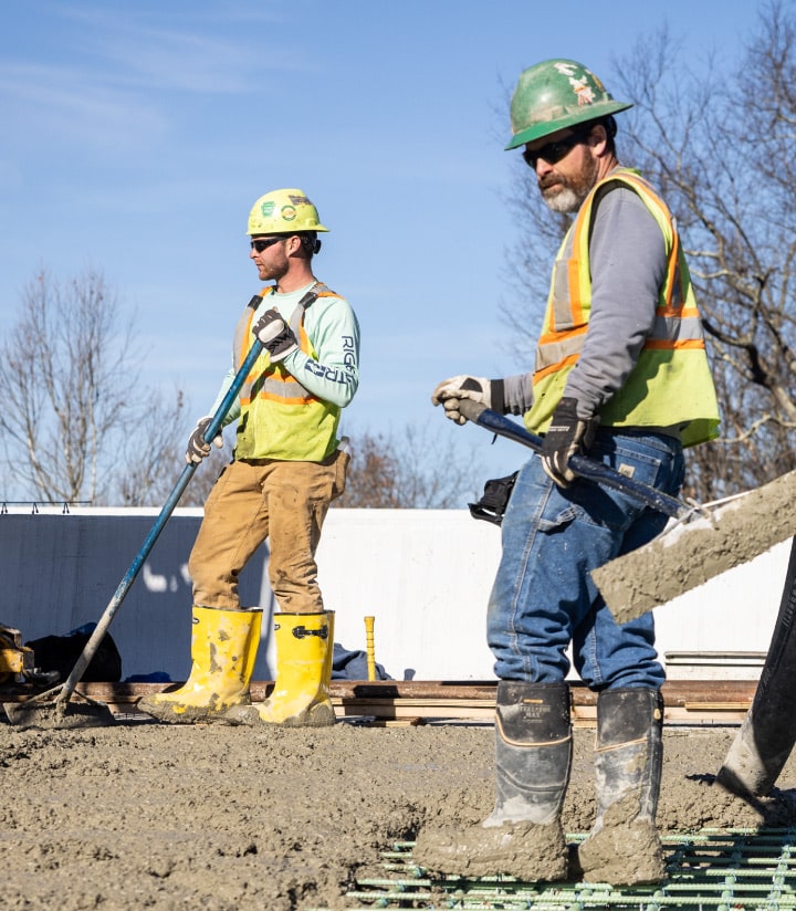 construction workers spreading concrete with shovels